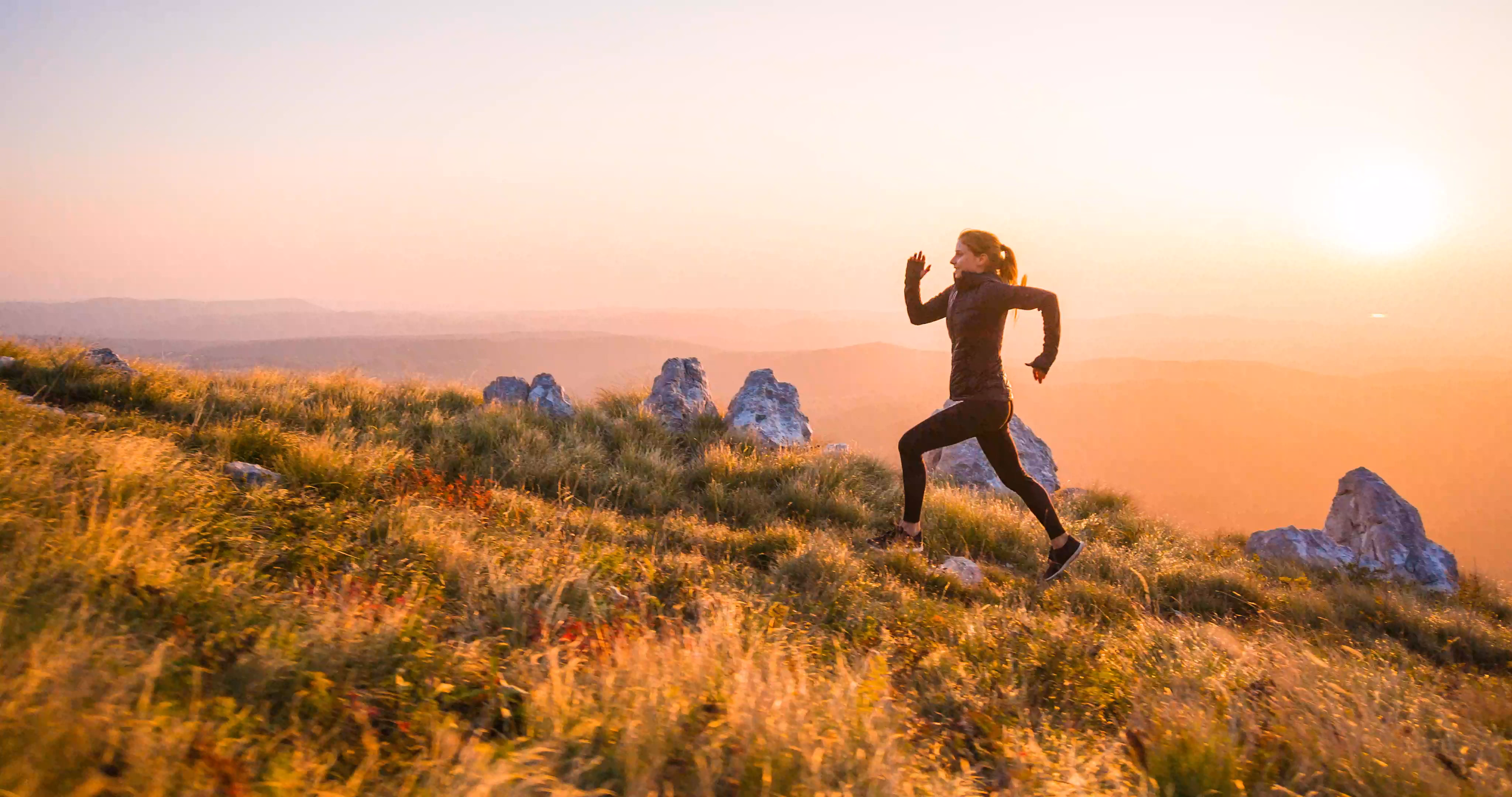 Runner moving across a mountain landscape at sunrise